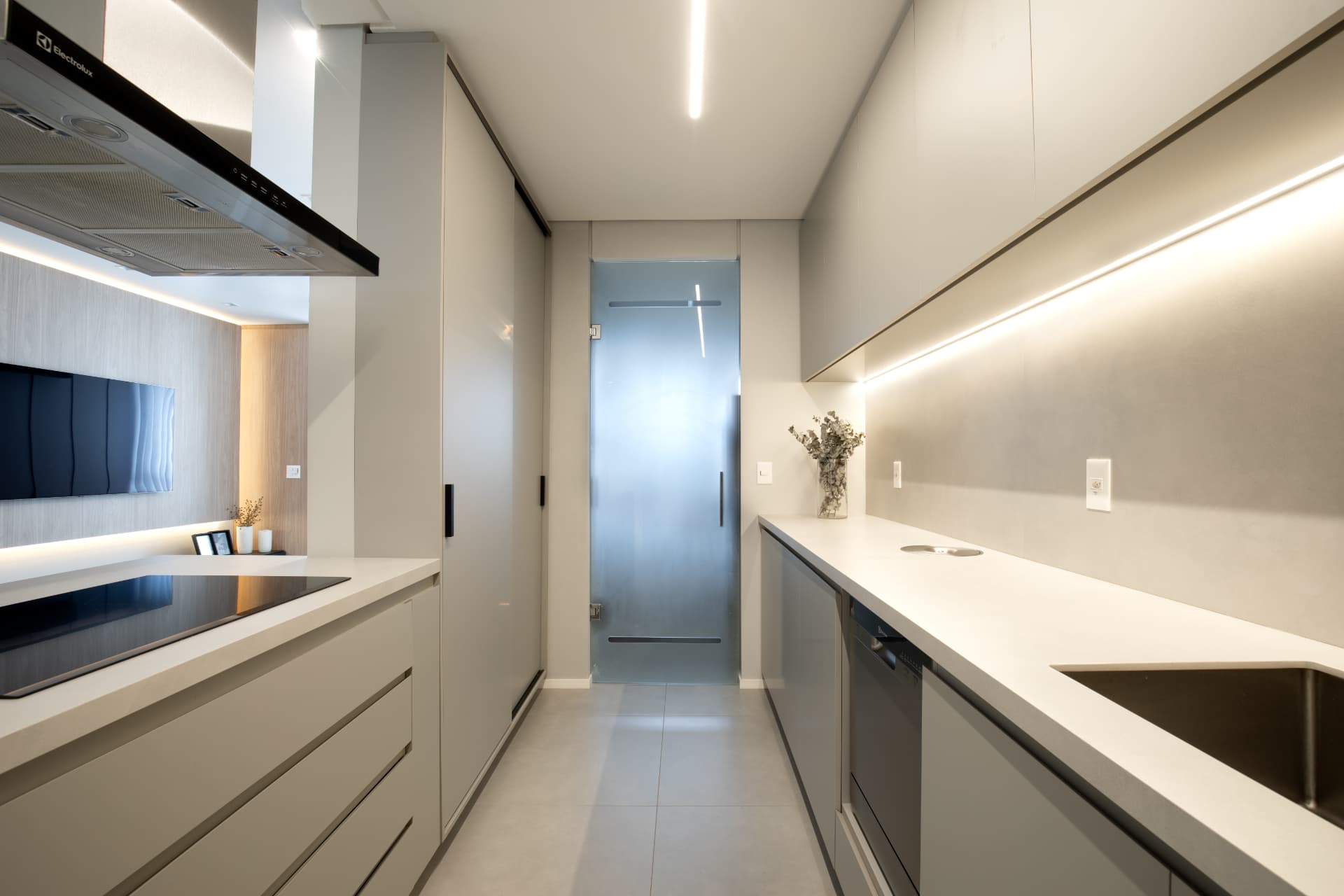 Cozinha planejada com armários lisos, bancada clara e iluminação linear